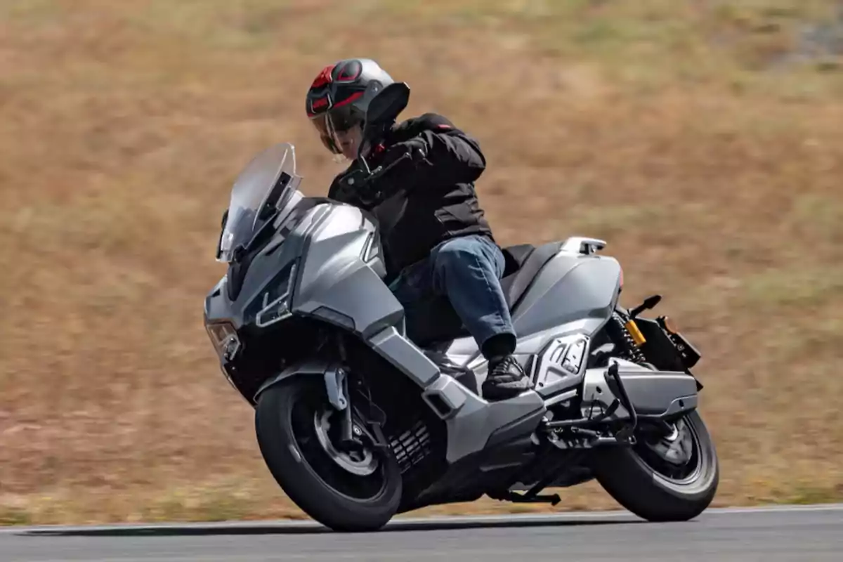 Persona conduciendo un scooter EFun gris en una carretera con fondo de pasto seco