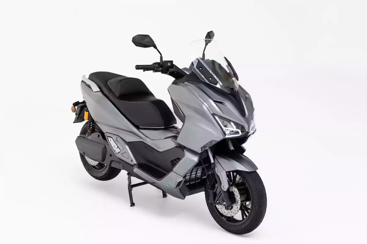 Motocicleta tipo scooter de color gris con parabrisas y asiento doble sobre fondo blanco Motocicleta tipo scooter de color gris con parabrisas y asiento doble sobre fondo blanco