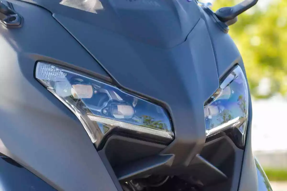 Detalle de los faros frontales de una motocicleta moderna de color negro con reflejos en el cristal Detalle de los faros frontales de una motocicleta moderna de color negro con reflejos en el cristal