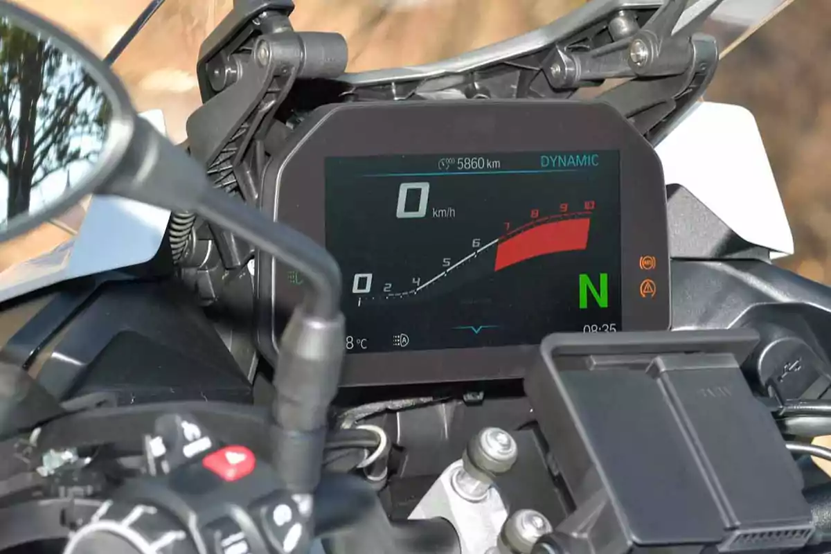 Tablero digital de motocicleta mostrando velocidad en cero, indicador de marcha en neutro y varios controles en el manillar Tablero digital de motocicleta mostrando velocidad en cero, indicador de marcha en neutro y varios controles en el manillar