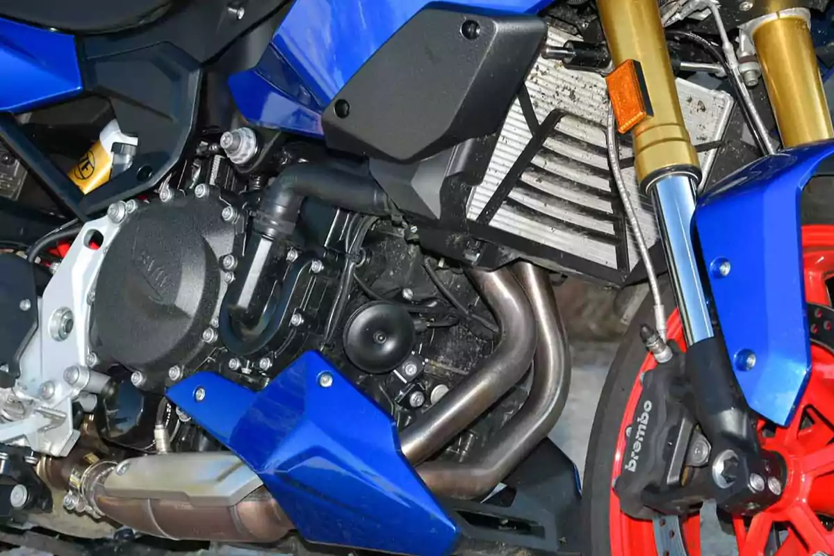 Detalle del motor y suspensión delantera de una motocicleta deportiva azul con llanta roja Detalle del motor y suspensión delantera de una motocicleta deportiva azul con llanta roja
