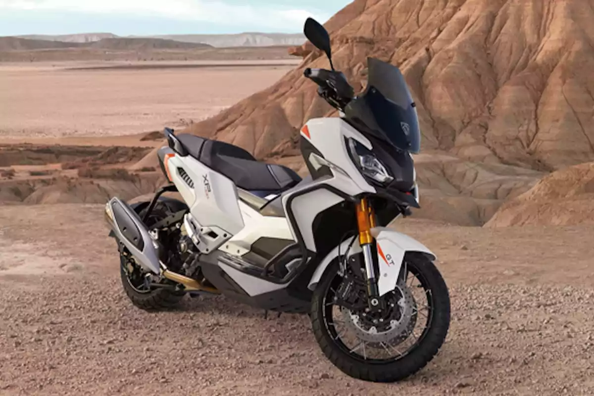Motocicleta blanca tipo adventure estacionada en un paisaje desértico con montañas de fondo Motocicleta blanca tipo adventure estacionada en un paisaje desértico con montañas de fondo