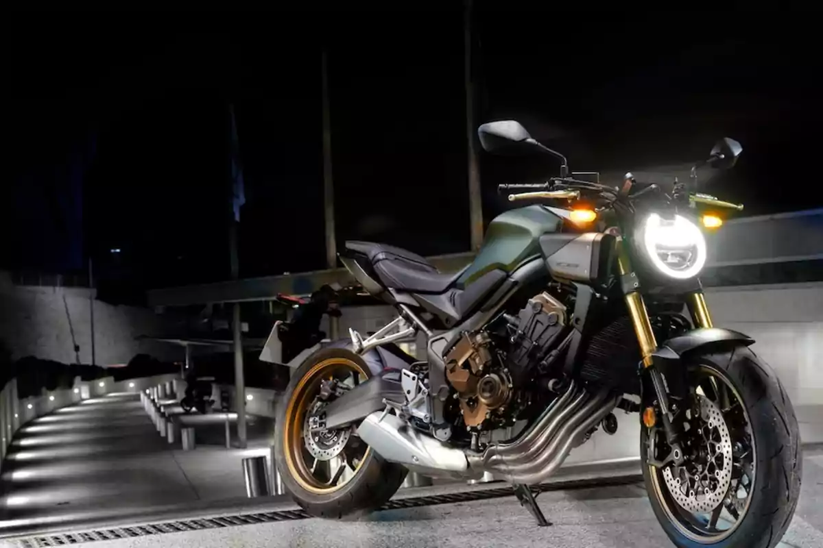 Motocicleta deportiva de color verde con detalles dorados estacionada en una calle iluminada durante la noche Motocicleta deportiva de color verde con detalles dorados estacionada en una calle iluminada durante la noche