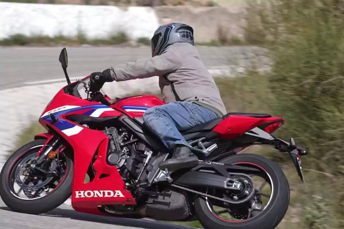 Persona conduint una motocicleta esportiva Honda vermella en una corba de carretera Persona conduint una motocicleta esportiva Honda vermella en una corba de carretera