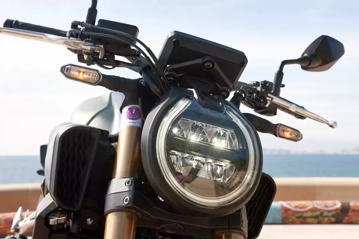 Motocicleta vista de frente con faro redondo encendido y fondo de mar Motocicleta vista de frente con faro redondo encendido y fondo de mar