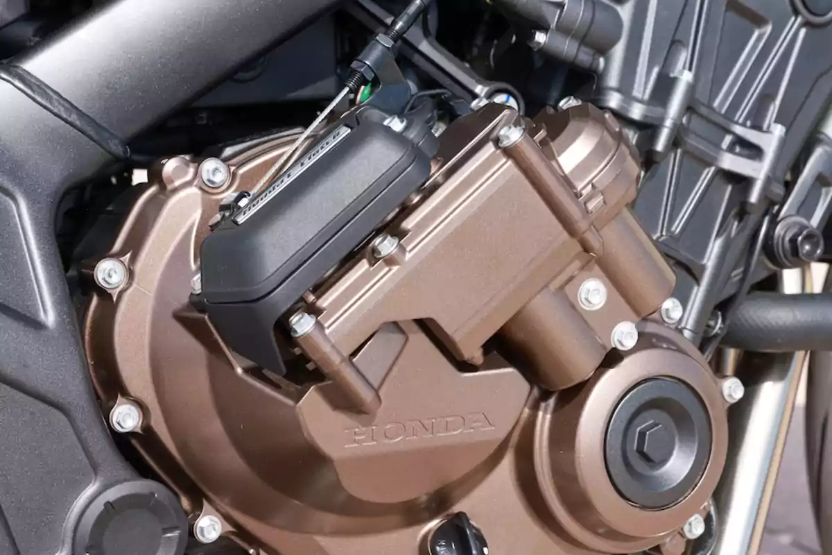 Detalle del motor de una motocicleta Honda con acabado metálico en color bronce y componentes mecánicos visibles Detalle del motor de una motocicleta Honda con acabado metálico en color bronce y componentes mecánicos visibles
