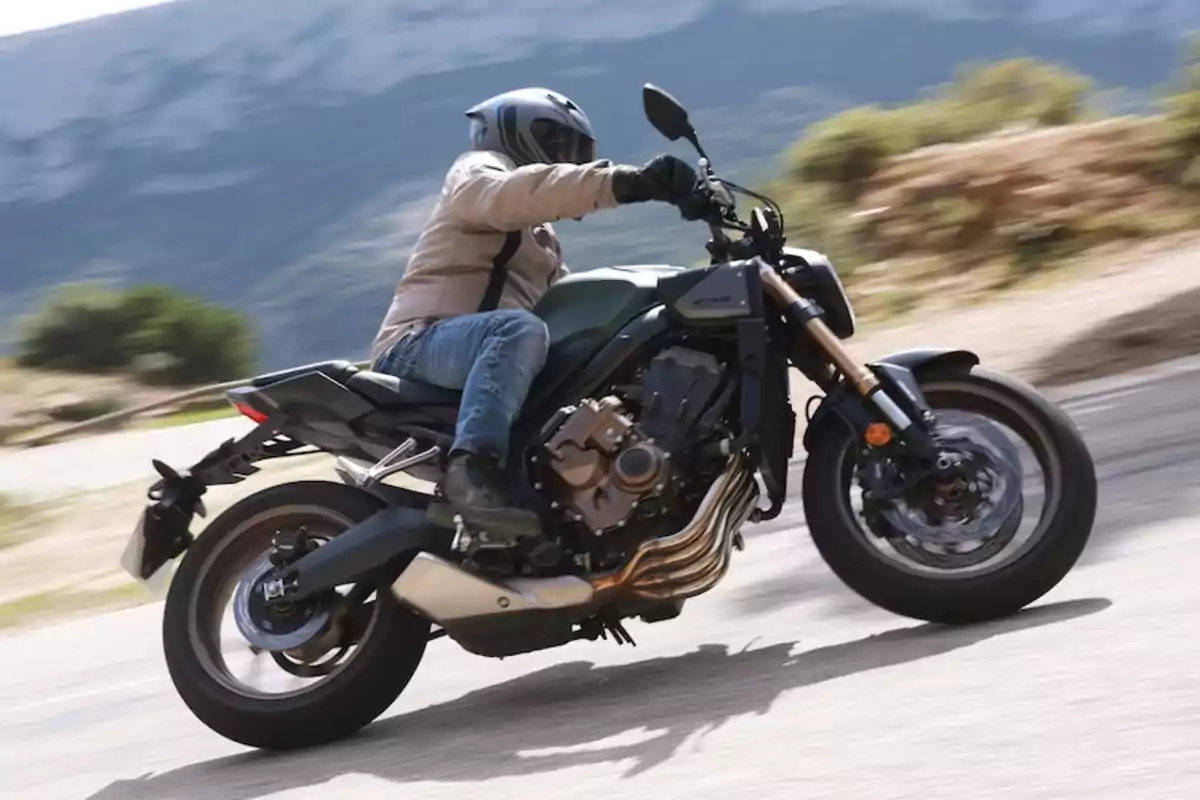 Persona conduciendo una motocicleta deportiva en una carretera de montaña con fondo de naturaleza y montañas desenfocadas