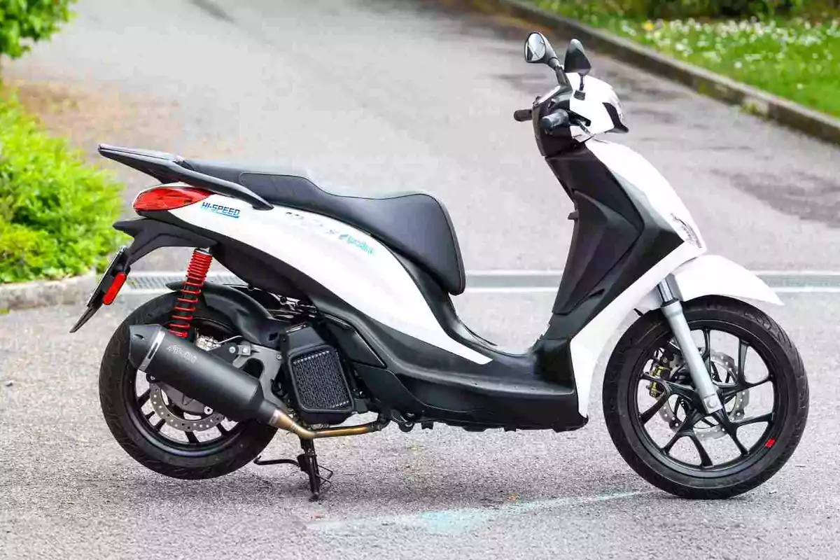 White and black scooter-type motorcycle parked on the asphalt White and black scooter-type motorcycle parked on the asphalt