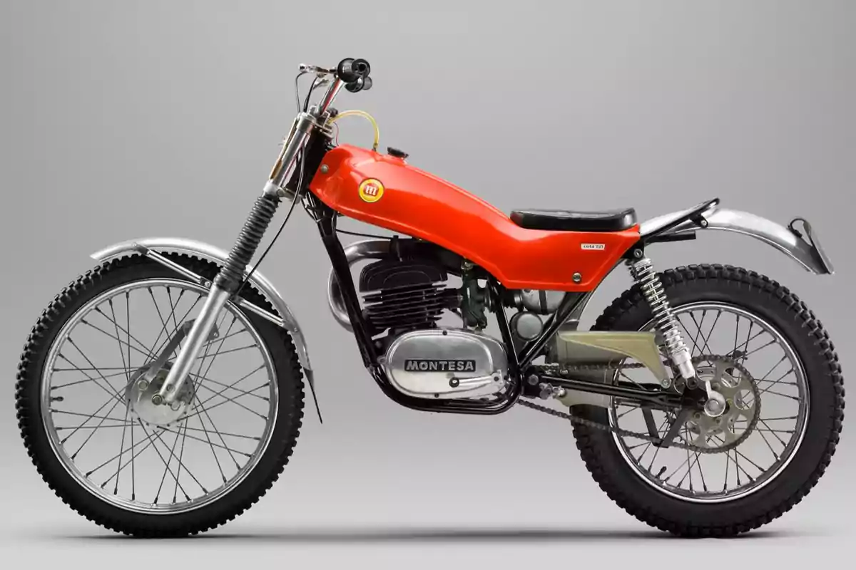 Motocicleta clásica Montesa de trial con tanque rojo y detalles cromados sobre fondo gris Motocicleta clásica Montesa de trial con tanque rojo y detalles cromados sobre fondo gris