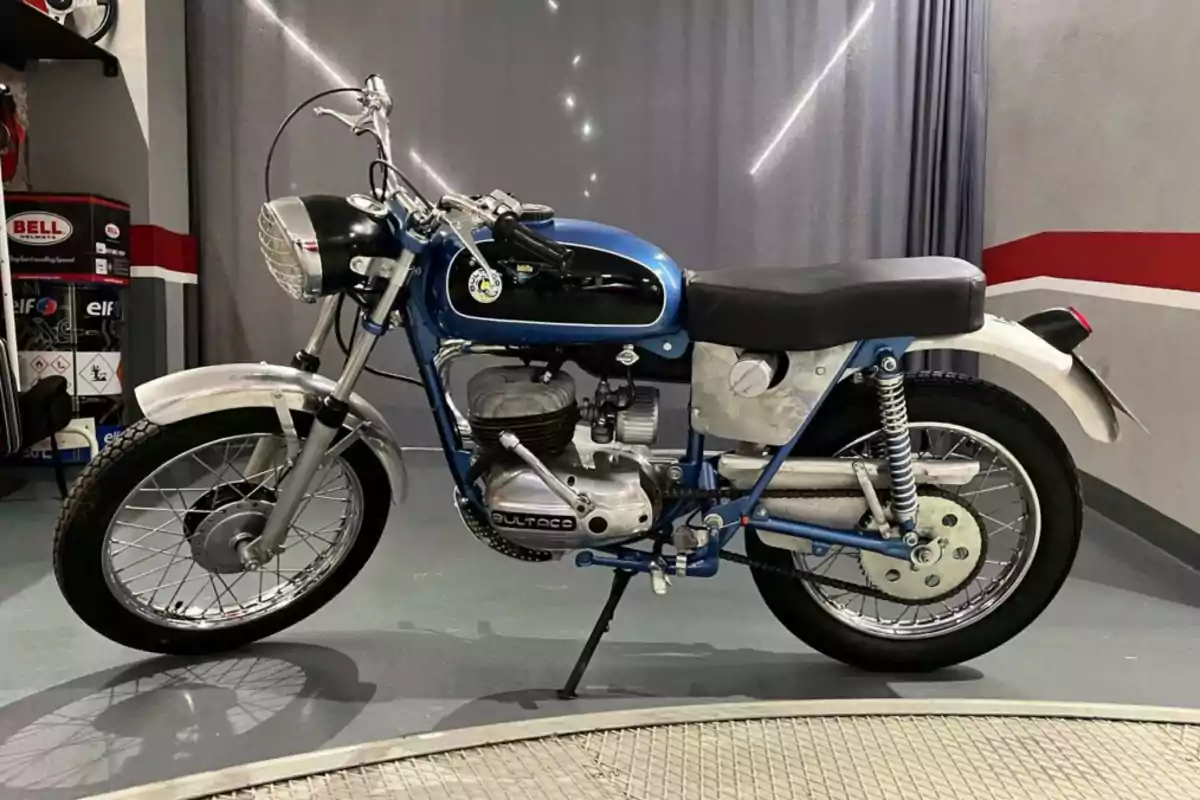 Motocicleta clásica Bultaco de color azul y negro con detalles cromados estacionada en un garaje moderno Motocicleta clásica Bultaco de color azul y negro con detalles cromados estacionada en un garaje moderno