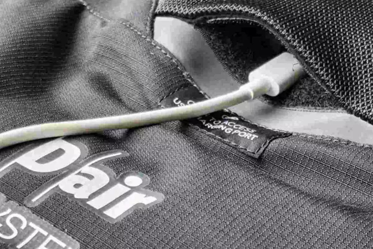 Detalle de una prenda deportiva con un cable USB conectado a un puerto oculto en el interior de un bolsillo Detalle de una prenda deportiva con un cable USB conectado a un puerto oculto en el interior de un bolsillo