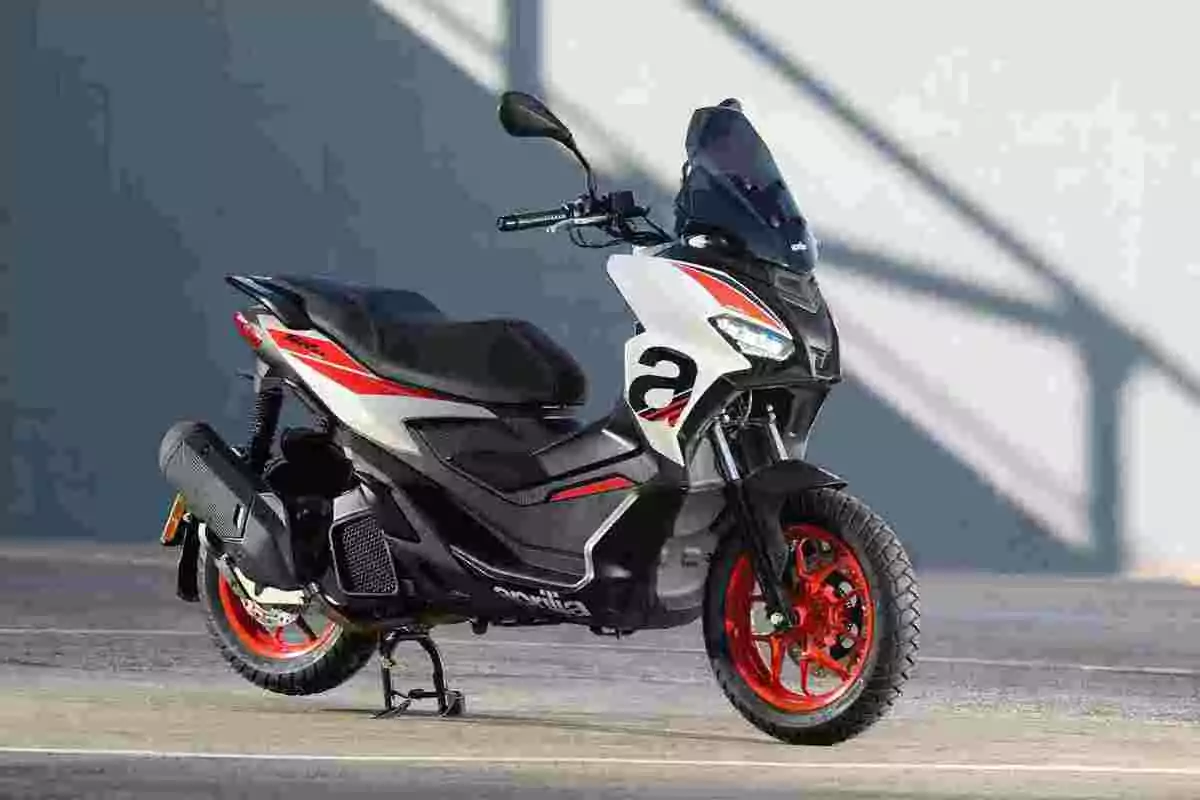 Motocicleta tipus scooter esportiva amb detalls en vermell, blanc i negre estacionada sobre l’asfalt Motocicleta tipus scooter esportiva amb detalls en vermell, blanc i negre estacionada sobre l’asfalt