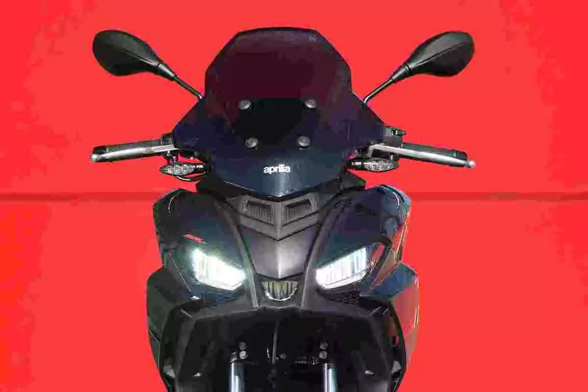 Motocicleta Aprilia negra vista de front amb fons vermell Motocicleta Aprilia negra vista de front amb fons vermell