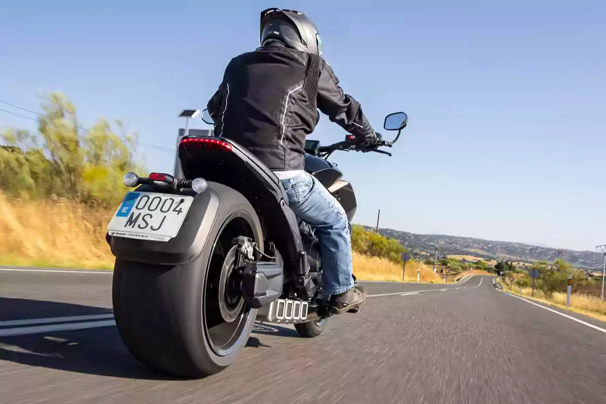 Persona conduciendo una motocicleta negra por una carretera despejada en un día soleado Persona conduciendo una motocicleta negra por una carretera despejada en un día soleado