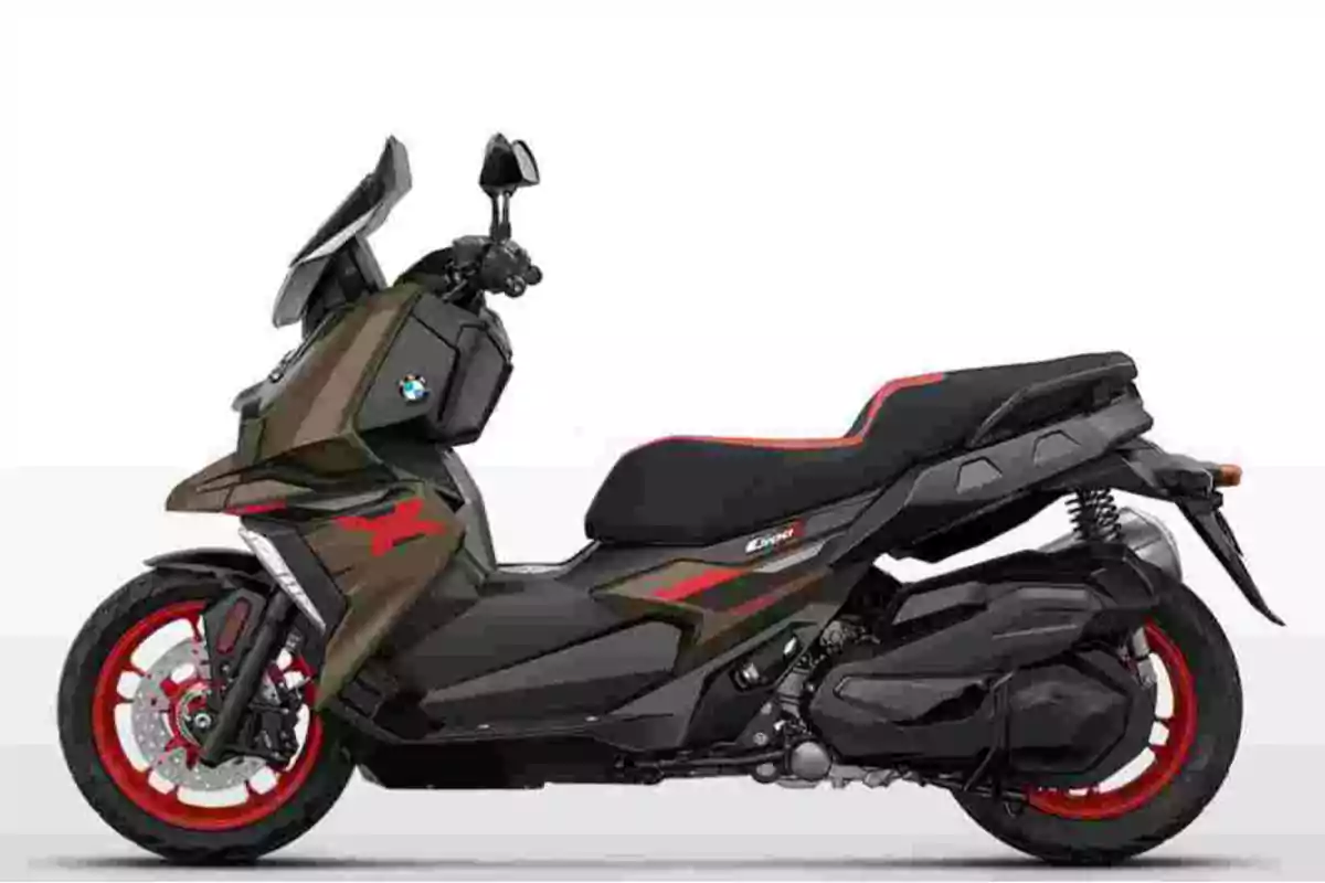 Motocicleta tipo scooter de color negro con detalles en rojo y verde, llantas rojas y asiento negro con ribete rojo, vista lateral sobre fondo blanco Motocicleta tipo scooter de color negro con detalles en rojo y verde, llantas rojas y asiento negro con ribete rojo, vista lateral sobre fondo blanco