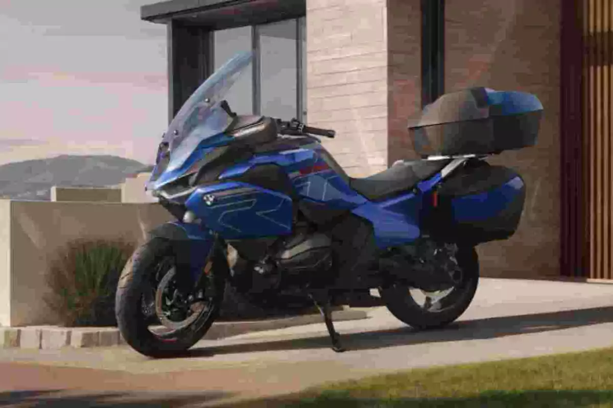 Motocicleta esportiva de color blau estacionada davant d’una casa moderna Motocicleta esportiva de color blau estacionada davant d’una casa moderna