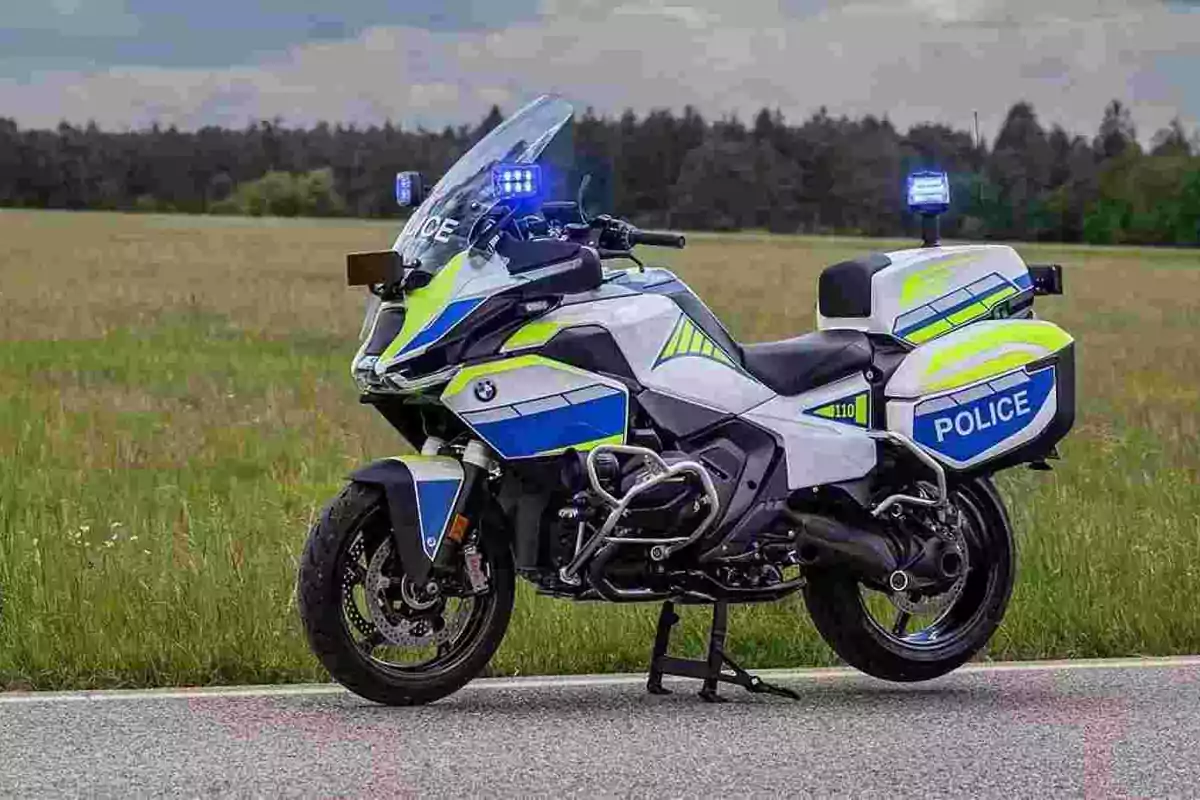 Motocicleta de policia BMW estacionada en una carretera al costat d’un camp amb els llums encesos Motocicleta de policia BMW estacionada en una carretera al costat d’un camp amb els llums encesos