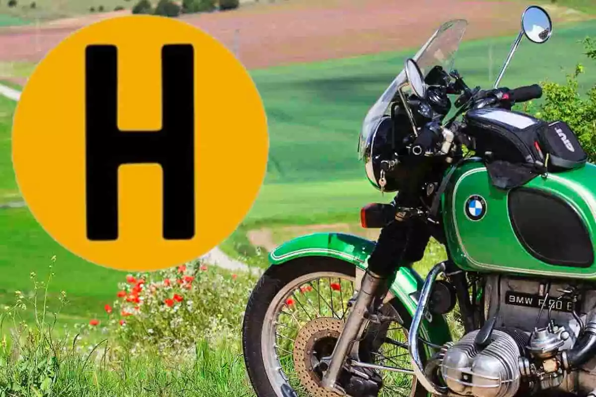 Motocicleta BMW verde estacionada en un campo con un gran círculo amarillo y una letra H negra