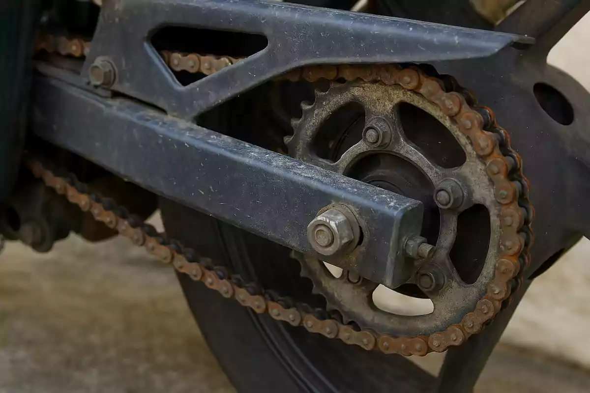Cadena y engranaje trasero de una motocicleta con signos de óxido y suciedad Cadena y engranaje trasero de una motocicleta con signos de óxido y suciedad