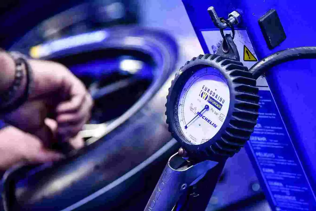 Mano ajustando la presión de una llanta con un manómetro Michelin en un entorno de taller automotriz Mano ajustando la presión de una llanta con un manómetro Michelin en un entorno de taller automotriz