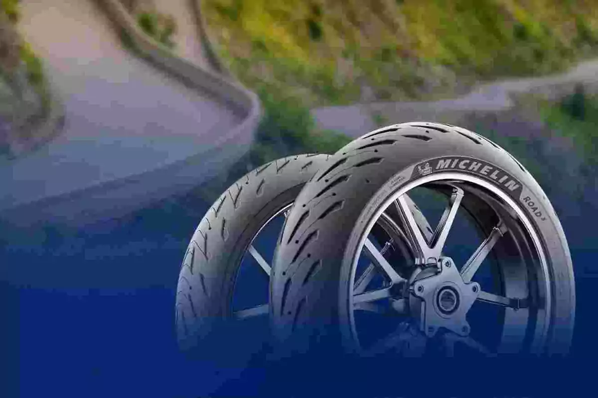 Dos llantas Michelin de motocicleta en primer plano con un camino curvo de fondo desenfocado Dos llantas Michelin de motocicleta en primer plano con un camino curvo de fondo desenfocado