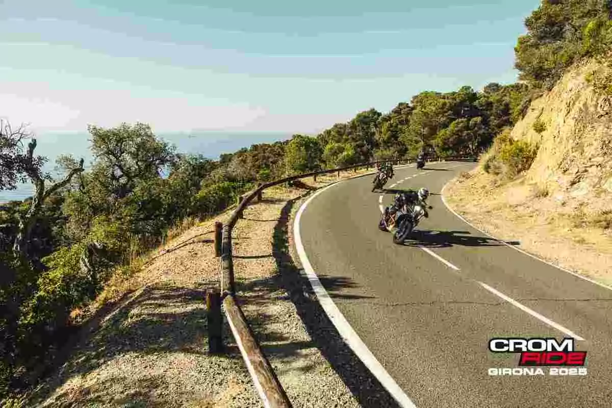Grupo de motociclistas recorriendo una carretera de montaña rodeada de árboles bajo un cielo despejado durante el evento Crom Ride Girona 2025 Grupo de motociclistas recorriendo una carretera de montaña rodeada de árboles bajo un cielo despejado durante el evento Crom Ride Girona 2025
