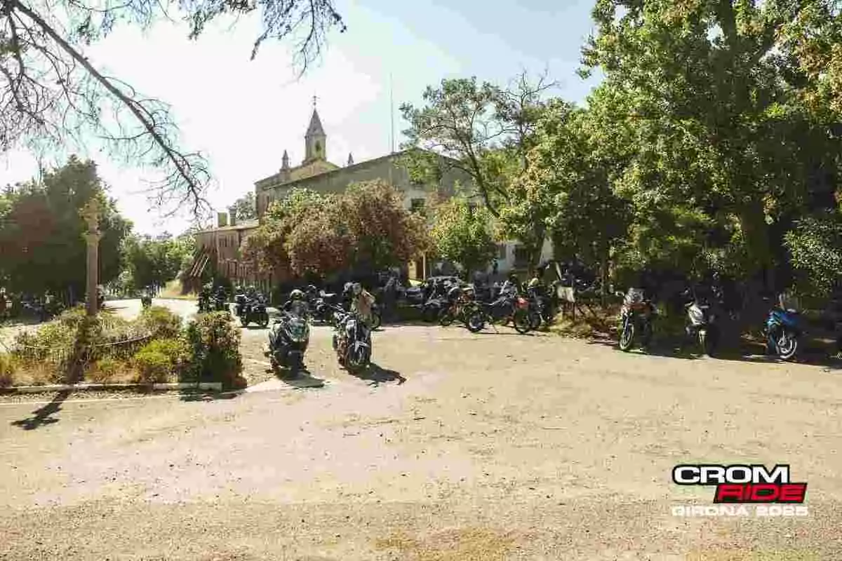Grupo de motocicletas aparcadas junto a un edificio antiguo rodeado de árboles en un día soleado durante el evento Crom Ride Girona 2023 Grupo de motocicletas aparcadas junto a un edificio antiguo rodeado de árboles en un día soleado durante el evento Crom Ride Girona 2023