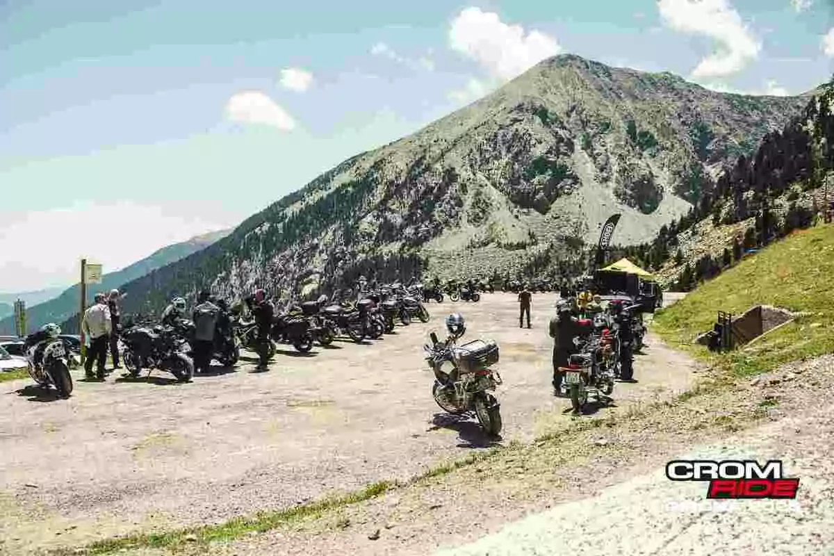 Grupo de motociclistas reunidos en un mirador de montaña con varias motos estacionadas y un paisaje de montañas al fondo Grupo de motociclistas reunidos en un mirador de montaña con varias motos estacionadas y un paisaje de montañas al fondo