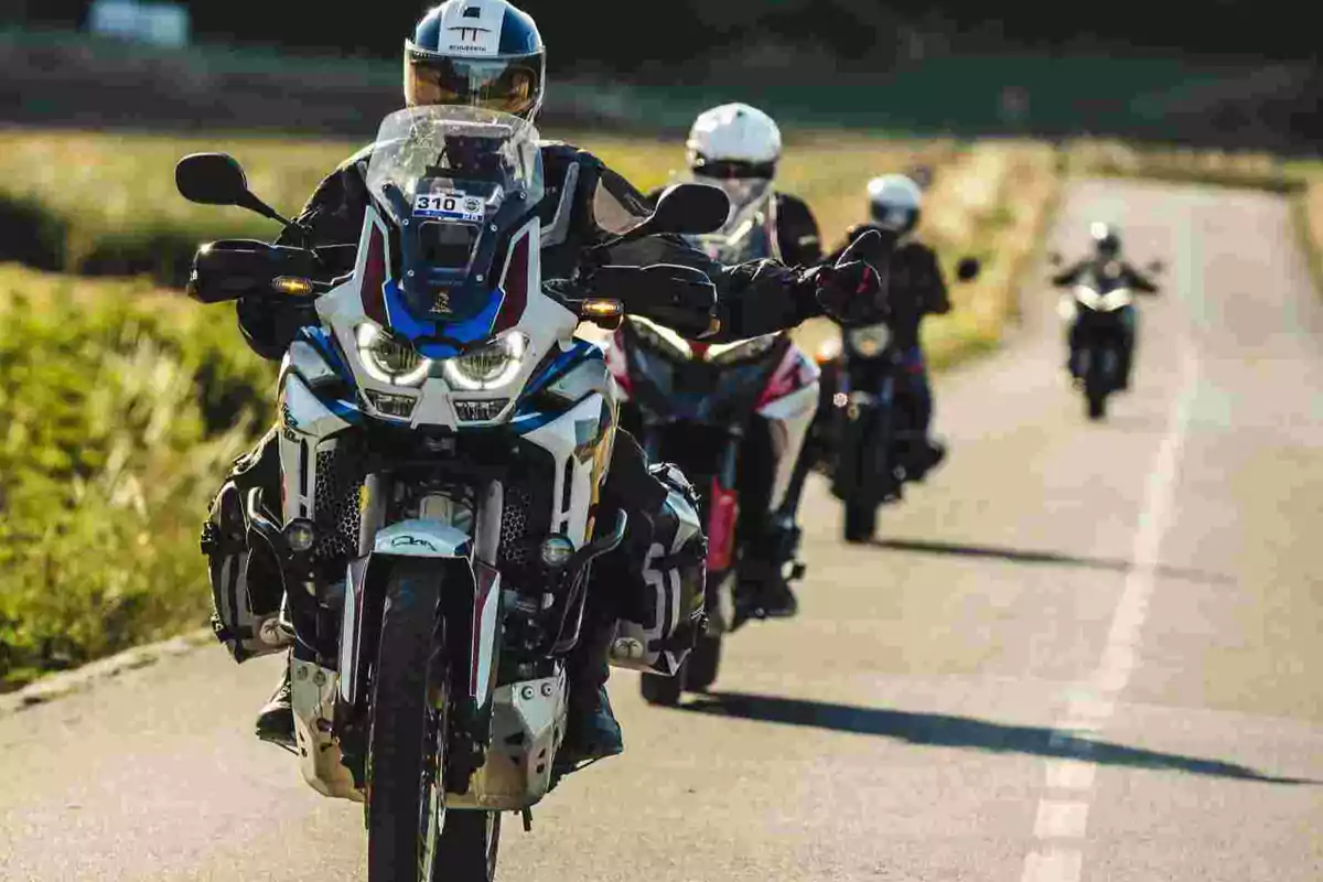 Grupo de motociclistas circulando por una carretera rural en un día soleado