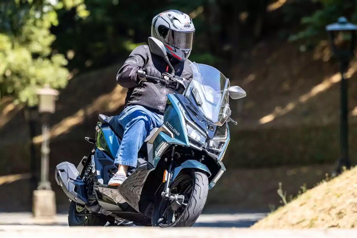 Persona conduciendo una motocicleta tipo scooter en una calle rodeada de árboles Persona conduciendo una motocicleta tipo scooter en una calle rodeada de árboles