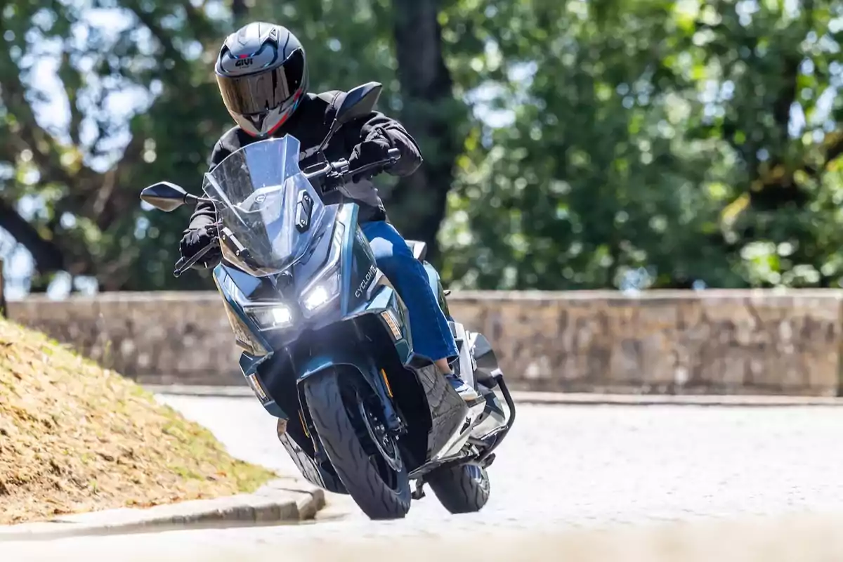 Persona conduciendo una motocicleta en una calle empedrada con árboles al fondo Persona conduciendo una motocicleta en una calle empedrada con árboles al fondo