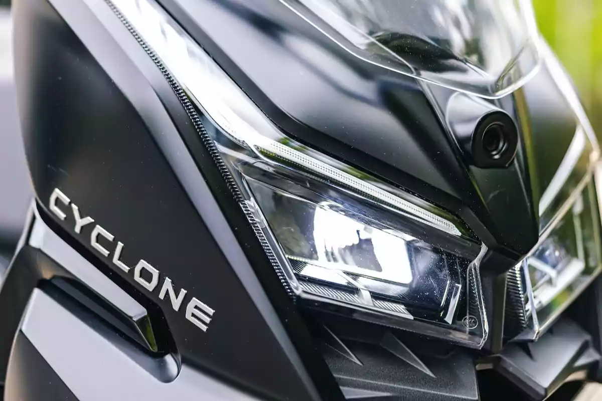 Detalle del faro delantero de una motocicleta negra con la palabra Cyclone en el carenado Detalle del faro delantero de una motocicleta negra con la palabra Cyclone en el carenado