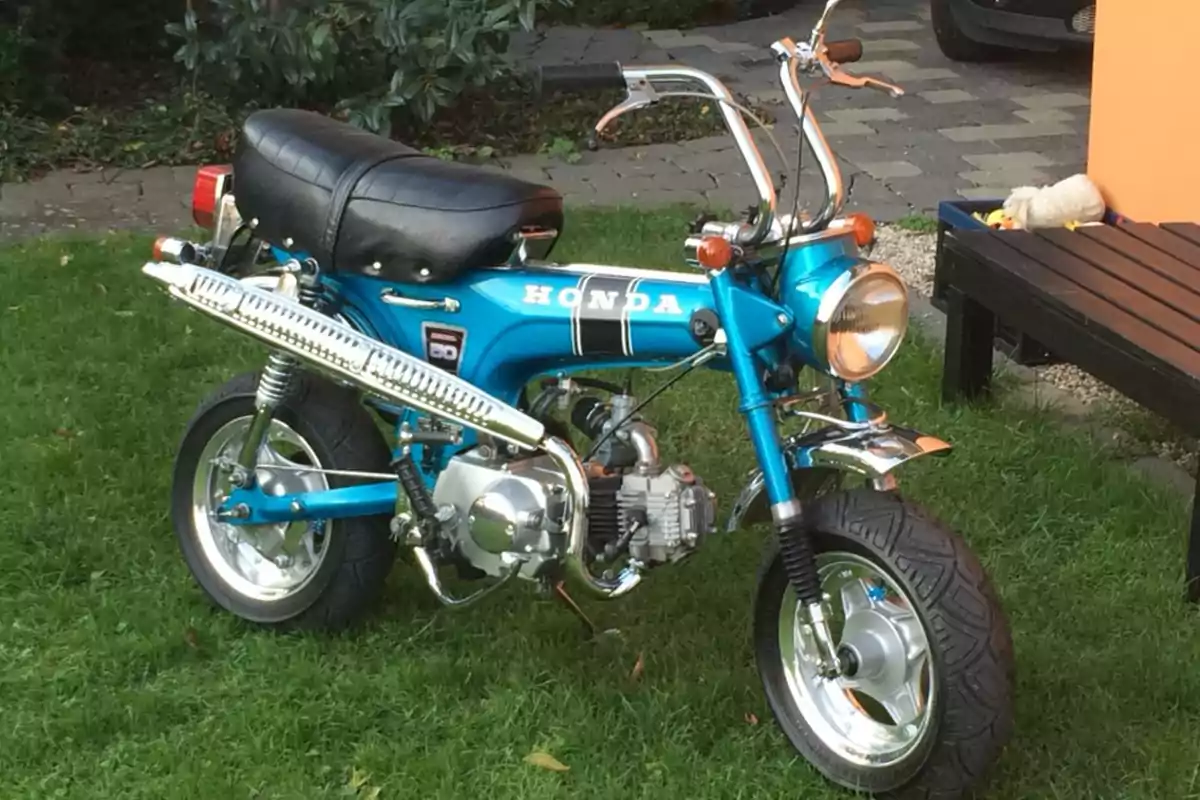 Motocicleta Honda azul de estilo clásico estacionada sobre césped en un jardín Motocicleta Honda azul de estilo clásico estacionada sobre césped en un jardín