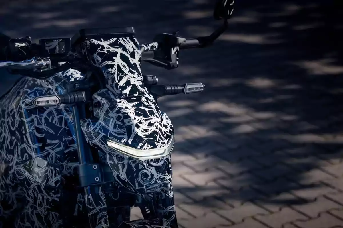 Motocicleta camuflada con diseño abstracto en blanco y negro estacionada sobre un pavimento de adoquines