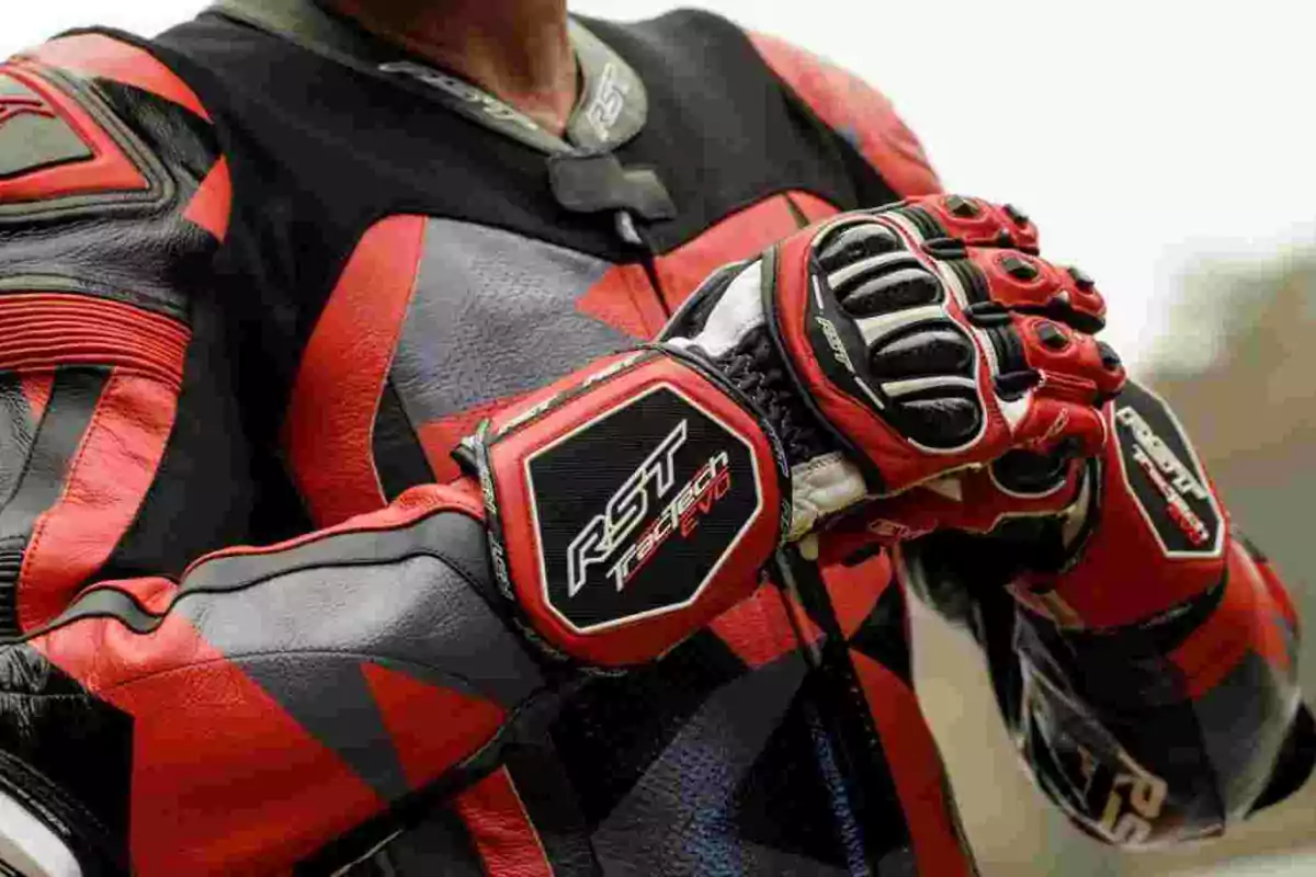 Person wearing a red and black motorcycle suit and gloves, adjusting their gloves.