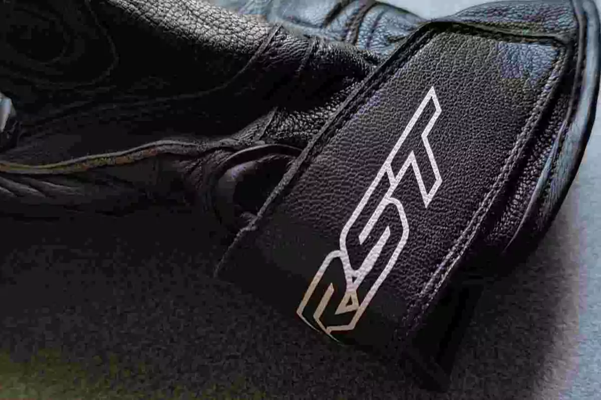 Guante de cuero negro con la marca RST visible en una correa Guante de cuero negro con la marca RST visible en una correa