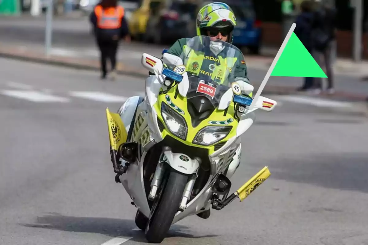 Motocicleta de la Guàrdia Civil de Trànsit circulant per una carretera amb una bandera verda a la part davantera
