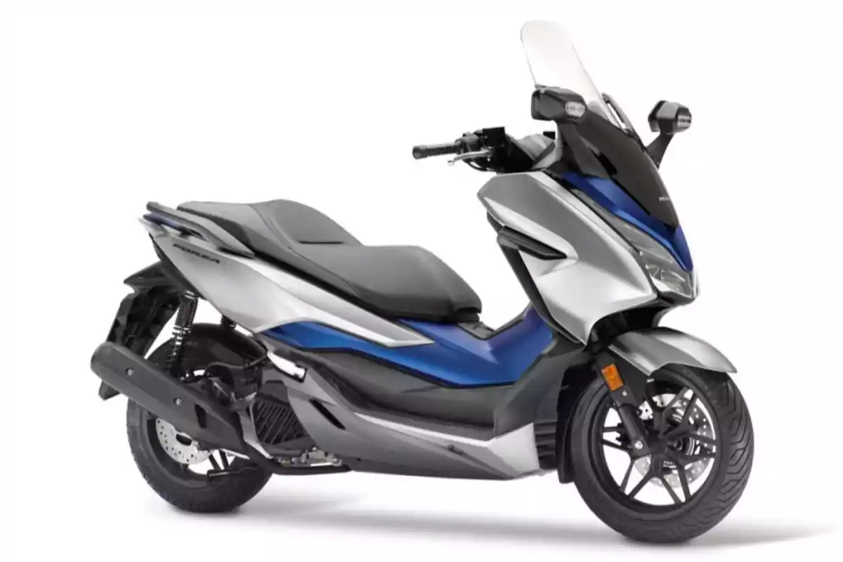 Motocicleta tipo scooter de color azul y plateado con parabrisas y asiento amplio sobre fondo blanco