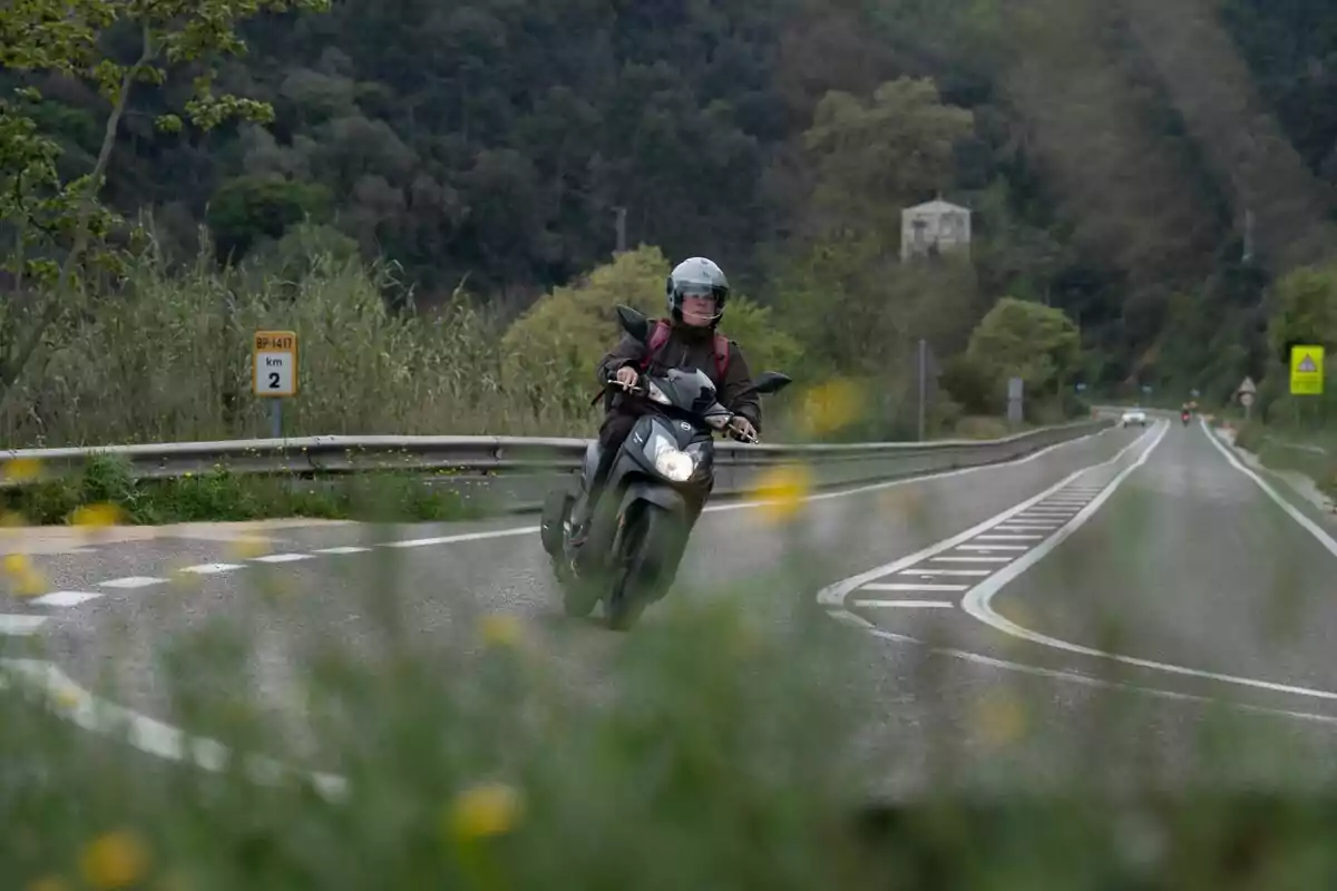 Persona conduciendo una motocicleta por una carretera rodeada de vegetación y curvas. Persona conduciendo una motocicleta por una carretera rodeada de vegetación y curvas.