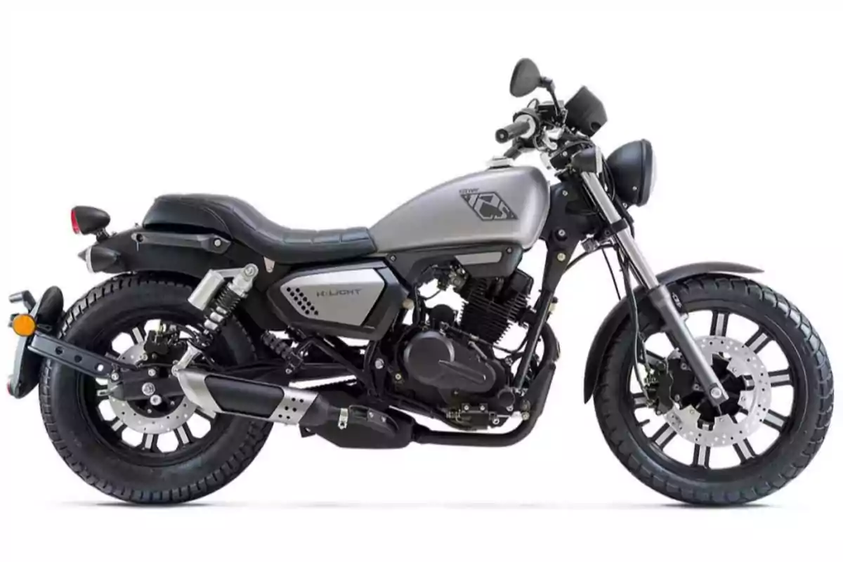 Motocicleta estilo cruiser de color gris con detalles en negro sobre fondo blanco