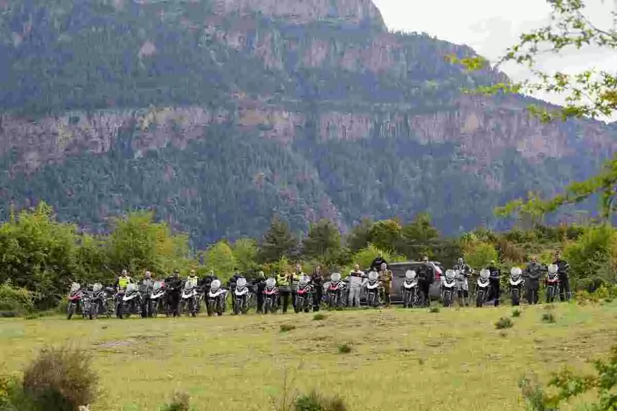 Group of people with motorcycles posing outdoors in a mountain landscape with vegetation Group of people with motorcycles posing outdoors in a mountain landscape with vegetation
