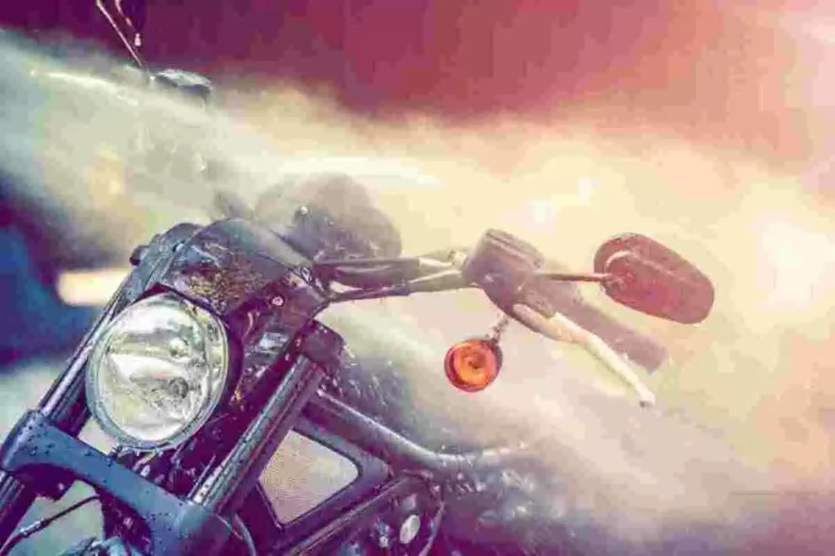 Motocicleta siendo lavada con un chorro de agua a presión bajo la luz del sol Motocicleta siendo lavada con un chorro de agua a presión bajo la luz del sol