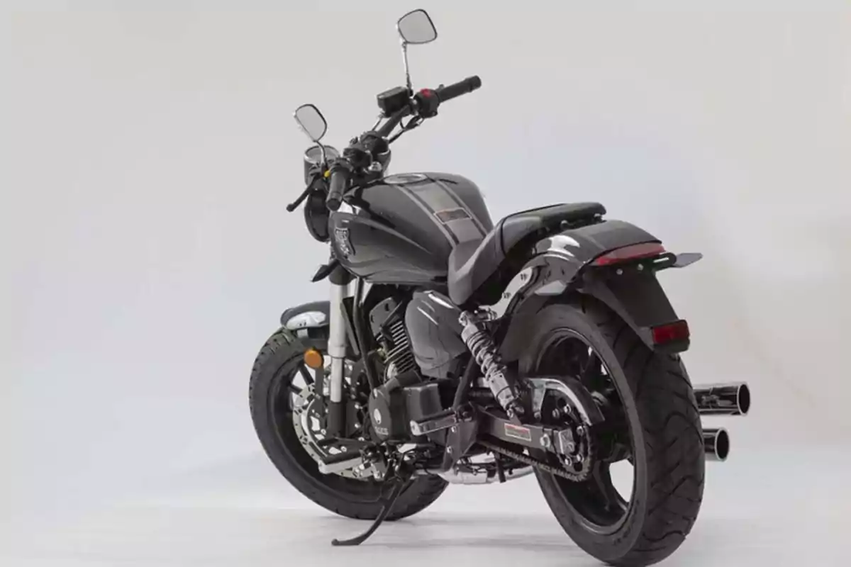 Motocicleta negra vista desde un ángulo trasero sobre un fondo blanco