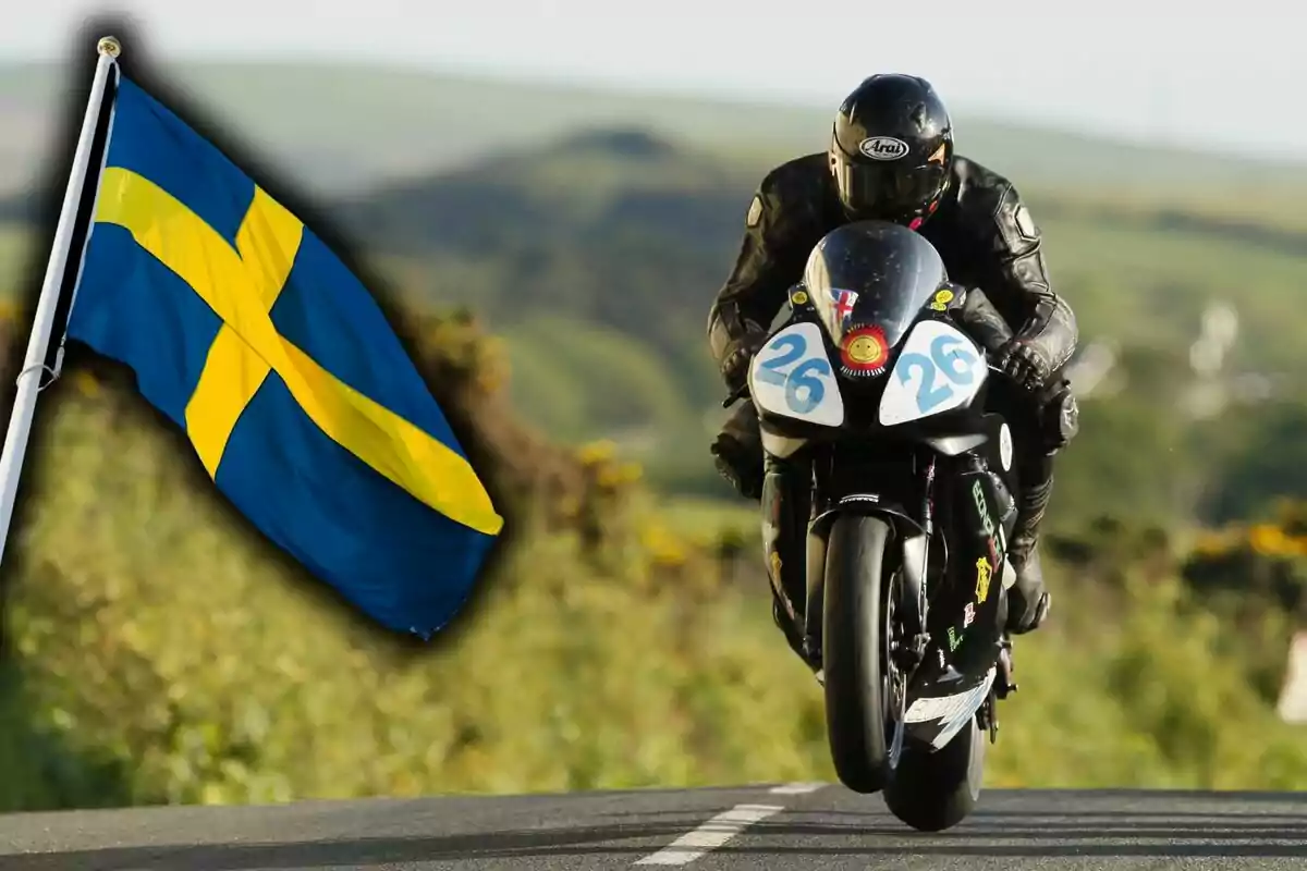 Motociclista en competencia sobre una carretera rural con una bandera de Suecia ondeando al lado izquierdo.