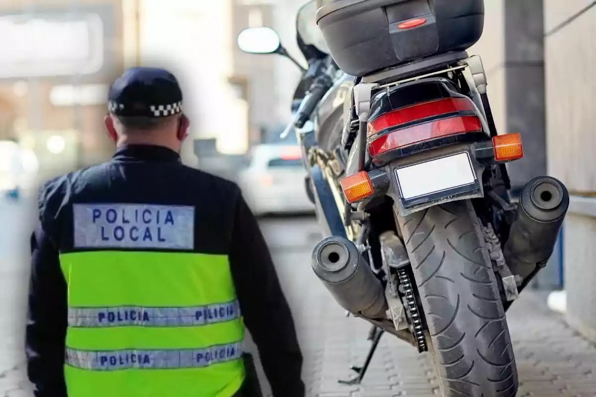 Un agente de la policía local de espaldas junto a una motocicleta estacionada en la acera
