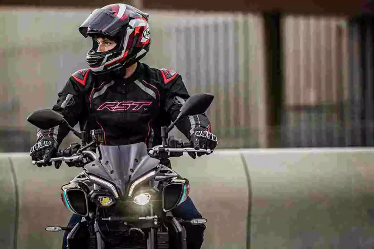 Persona con casco y chaqueta de motociclista conduciendo una moto negra mientras mira hacia un lado Persona con casco y chaqueta de motociclista conduciendo una moto negra mientras mira hacia un lado