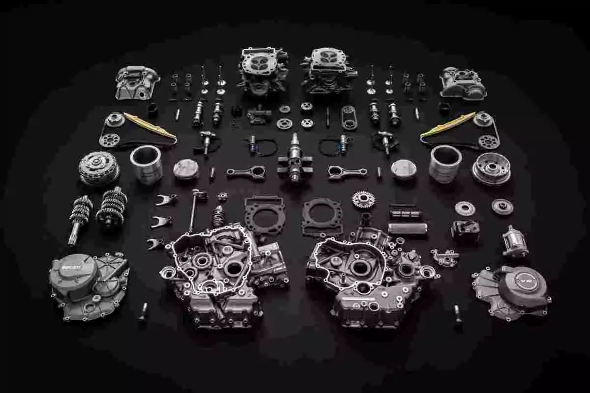 Piezas de un motor de motocicleta completamente desarmado y organizadas sobre una superficie negra Piezas de un motor de motocicleta completamente desarmado y organizadas sobre una superficie negra