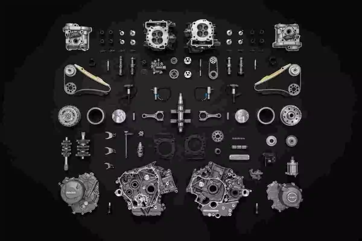 Piezas de un motor de motocicleta completamente desarmado y organizadas simétricamente sobre un fondo negro Piezas de un motor de motocicleta completamente desarmado y organizadas simétricamente sobre un fondo negro