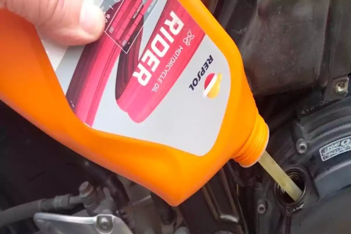 Persona vertiendo aceite para motocicleta Repsol Rider en el motor de una moto Persona vertiendo aceite para motocicleta Repsol Rider en el motor de una moto