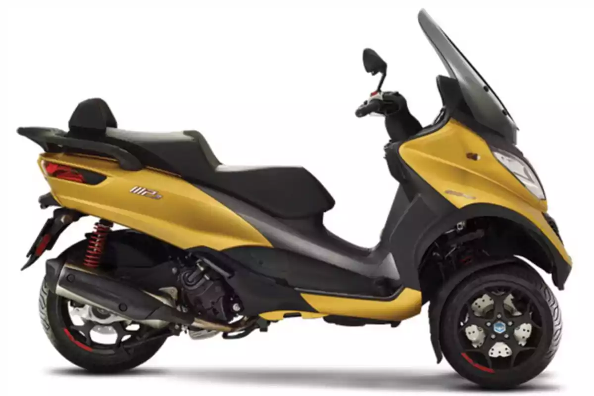 Motocicleta scooter de tres ruedas color dorado con parabrisas y asiento negro sobre fondo blanco